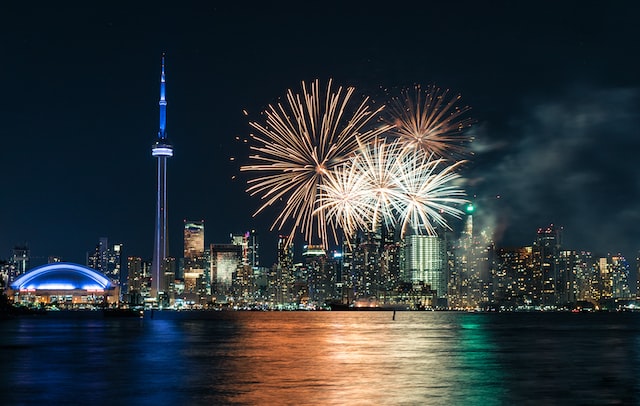toronto skyline looking across Lake Ontario at night with lots of fireworks